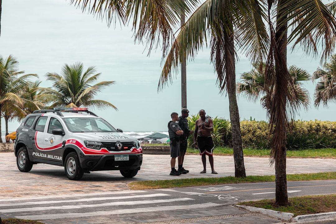 Police officers and patrol car near the beach.